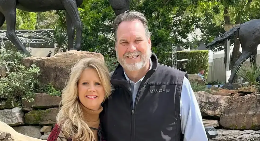 Smiling couple posing outdoors near sculptures.