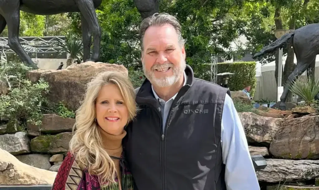 Smiling couple posing outdoors near sculptures.