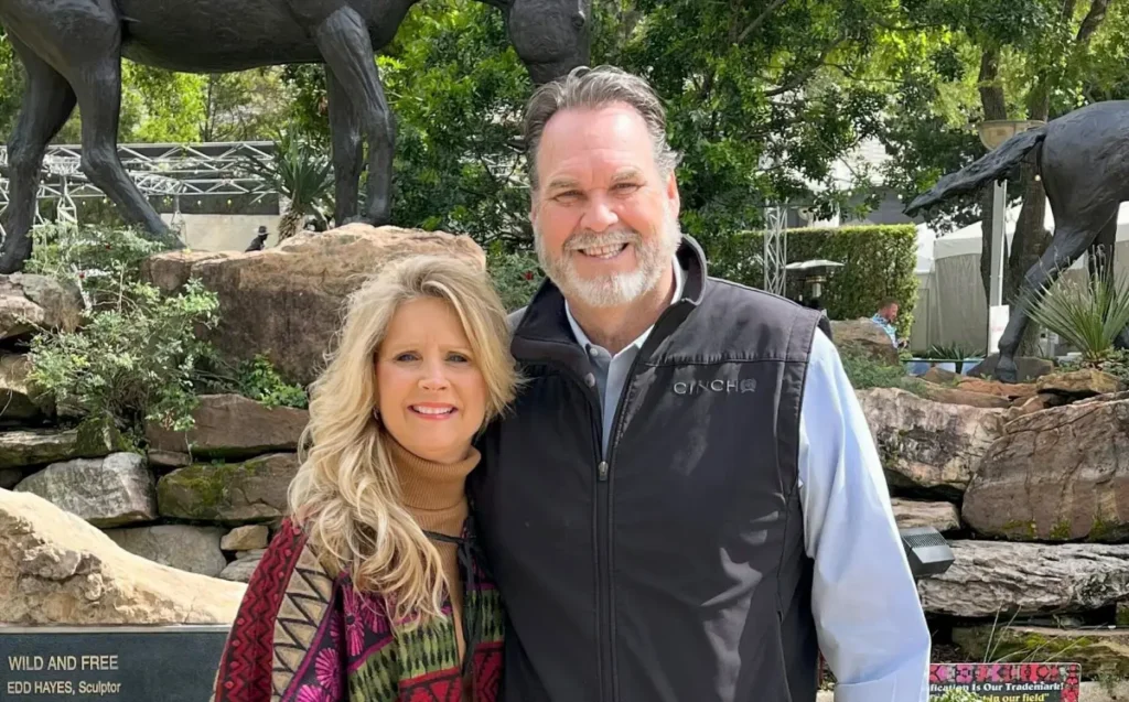 Smiling couple posing outdoors near sculptures.